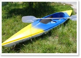 Yellow and blue fibreglass kayak with a paddle, representative of the NFP kayak range