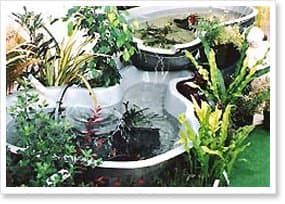 Tiered fibreglass garden pond with water spilling between levels and planting around it