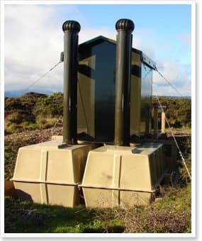 Alpine toilet building on a fibreglass tank base with twin vent pipes on an exposed hillside