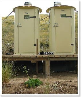 Two cream environmental toilets on a timber deck over a holding tank in tussock country